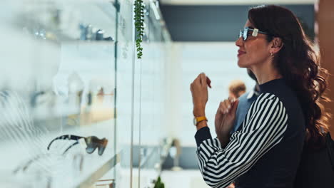 a woman and a man look at glasses in a store