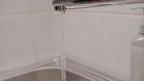 man washing her hands with liquid soap in the bathroom