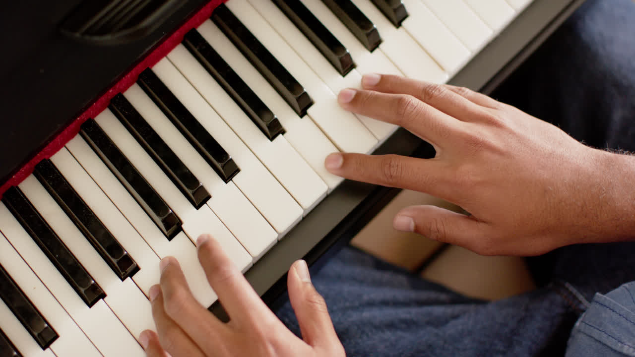 cerca de las manos de un hombre biracial tocando el piano en casa, en cámara lenta