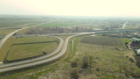 Luftaufnahme,-Die-Drohne-Fliegt-Entlang-Paralleler-Autobahnstraßen-S7-Cedry-Road-Und-Infinity-Road-Interchange-In-Polen,-Lichtlandschaft