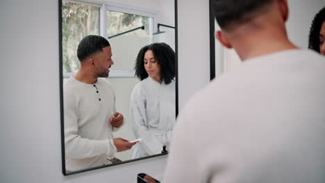 couple in bathroom brushing teeth in mirror reflection