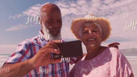 Animation-of-joy-over-happy-diverse-senior-couple-taking-selfie-on-beach