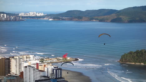 parapentes con paracaídas volando sobre santos, playa brasil y edificios frente al mar