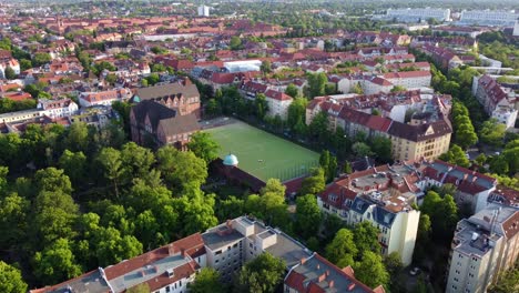 green soccer field in the middle of the capital of germany wonderful aerial view flight rising up drone footage
of berlin friedenau summer 2022