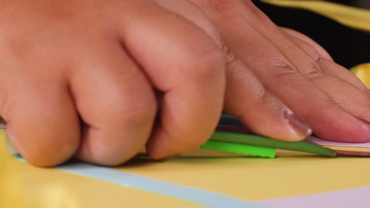 Close up shot of fingers precisely folding colorful paper sheets during a creative origami session