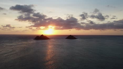 toma cinematográfica de zoom-out del amanecer detrás de dos islas frente a la costa de lanikai en la isla de oahu en hawaii