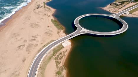 drone capturando auto acercándose al puente en el océano en garzon, maldonado, uruguay