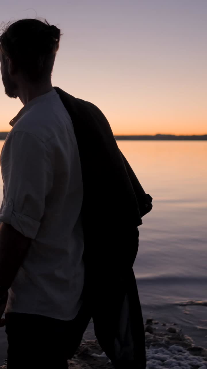 Man Silhouetted Against Sunset by the Water