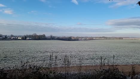frosty white winter morning farmland meadow under cloudy chilly autumn sunrise, panoramic shot
