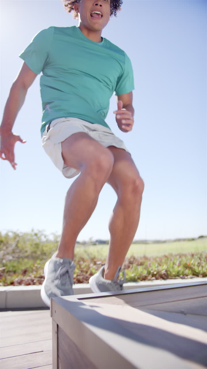 Vertical video: A fit biracial man is performing box jump exercise