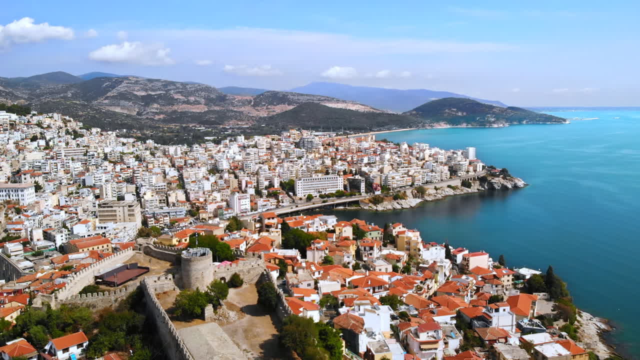 Aerial view of Kavala, a lot of buildings, Aegean sea coast, sea port, ancient fort, green hills in the distance, Greece