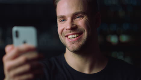 close up of positive guy enjoying videocall talk on smartphone indoors.