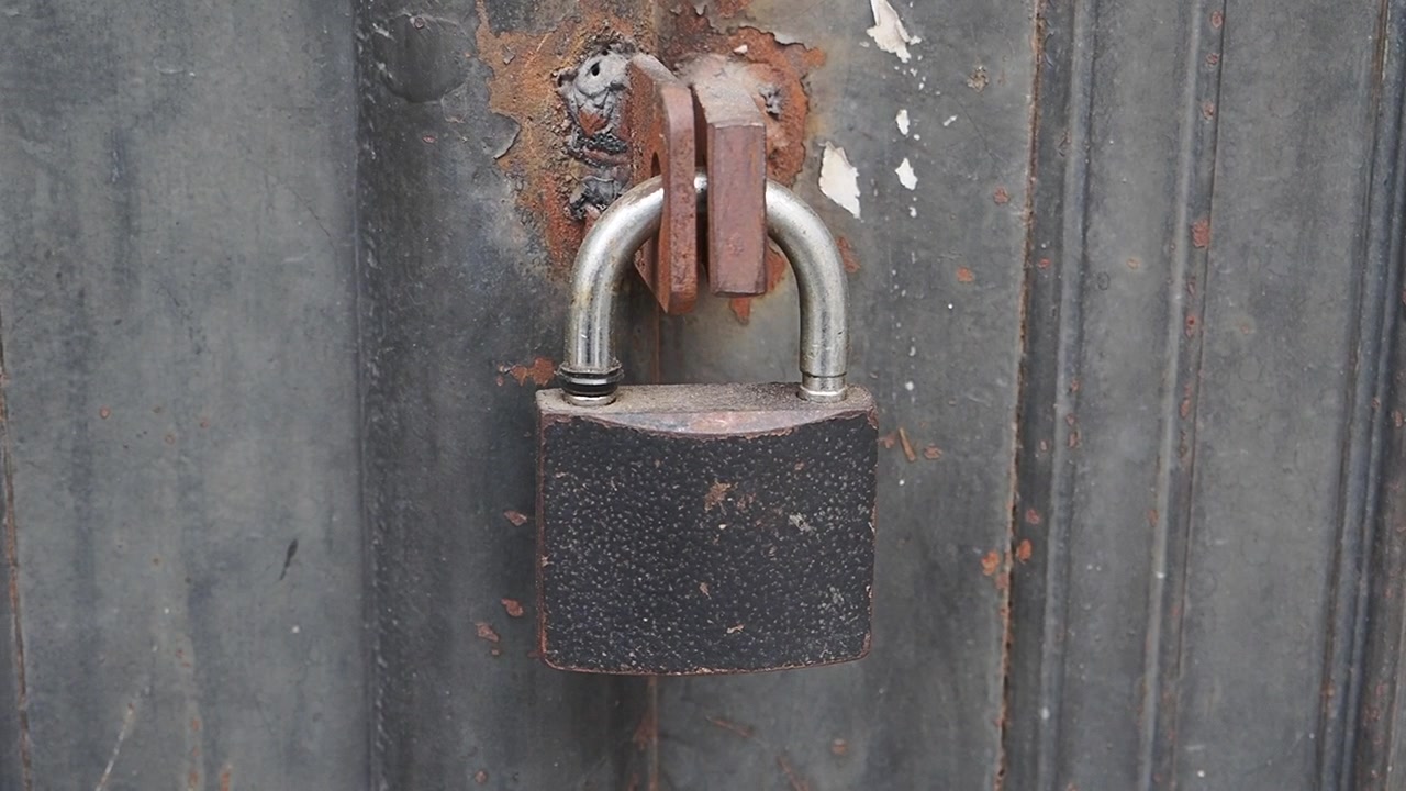 Old Rusty Padlock Secured on a Weathered Metal Gate