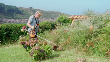 Senior-man-in-protective-shield-mask-mowing-grass-with-mower