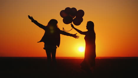 Mom-And-Daughter-Are-Having-Fun-At-Sunset-Dancing-And-Holding-Balloons