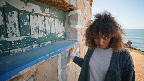 sad lady contemplating stoned building closeup. curly brunette model posing