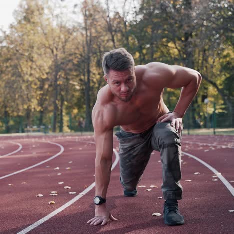 bearded sportsman on a sports track. handsome man with muscular body exercising outdoors on the stadium. sprinter runner preparing for run.
