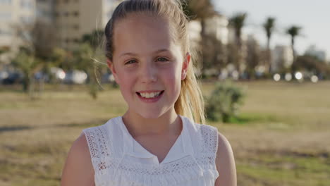 portrait beautiful little girl smiling happy enjoying relaxed summer vacation day on warm sunset urban park wind blowing hair