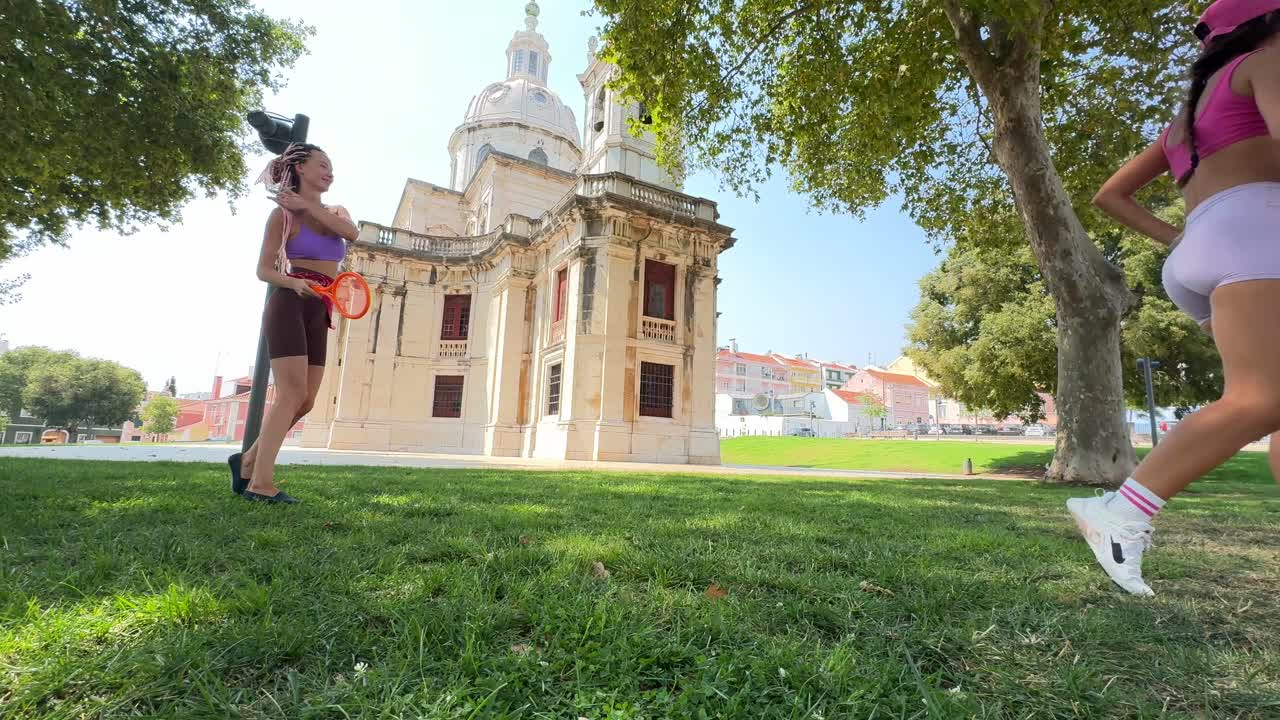 Two women playing in a park near a historical building