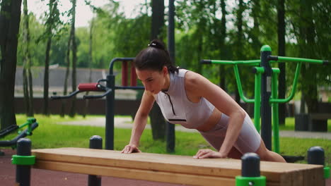 atleta femenina haciendo flexiones de banco para el entrenamiento de fuerza en el parque de la ciudad en verano. mujer deportiva entrenando al aire libre