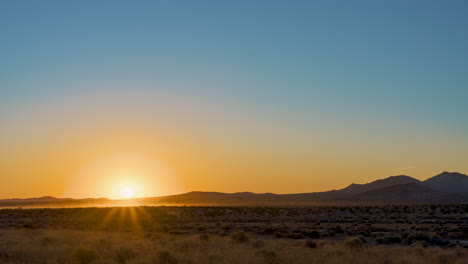 dawn breaks in this epic sunrise on a hot, clear summer morning over the mojave desert landscape - grazing herd of sheep causes dust to raise in the distance