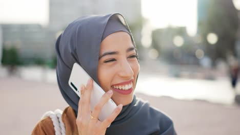 young woman in hijab talking on a smartphone and smiling outdoors