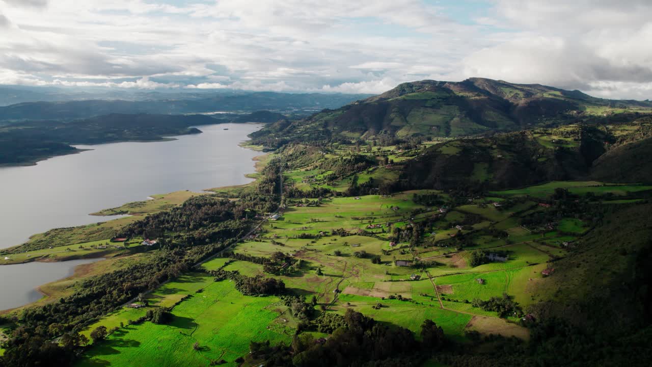 Static aerial shot showing green valleys and reflective waters of Tominé Reservoir in Guatavita, Colombia