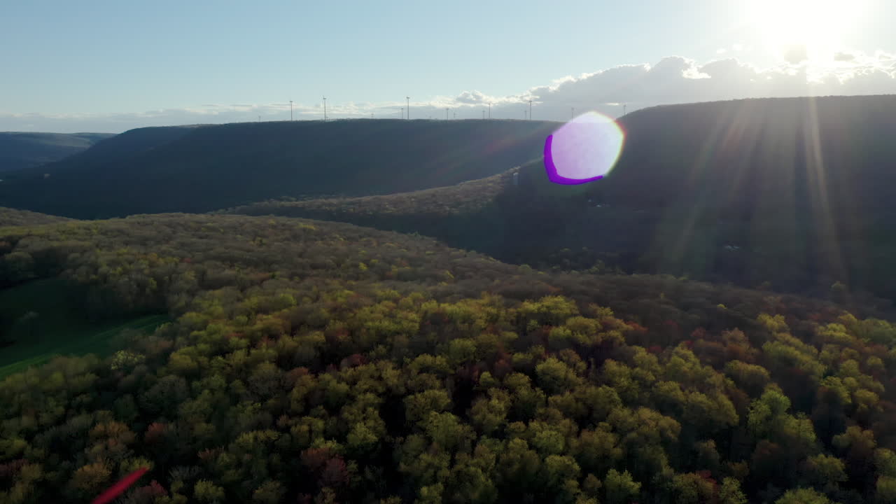 멀리 떨어진 산에 풍력 터빈이 있는 일몰의 녹색 숲까지 부드러운 영화 팬