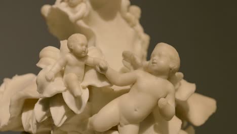 close up of an ivory cherub statue sitting on a flower and holding another cherub's hand