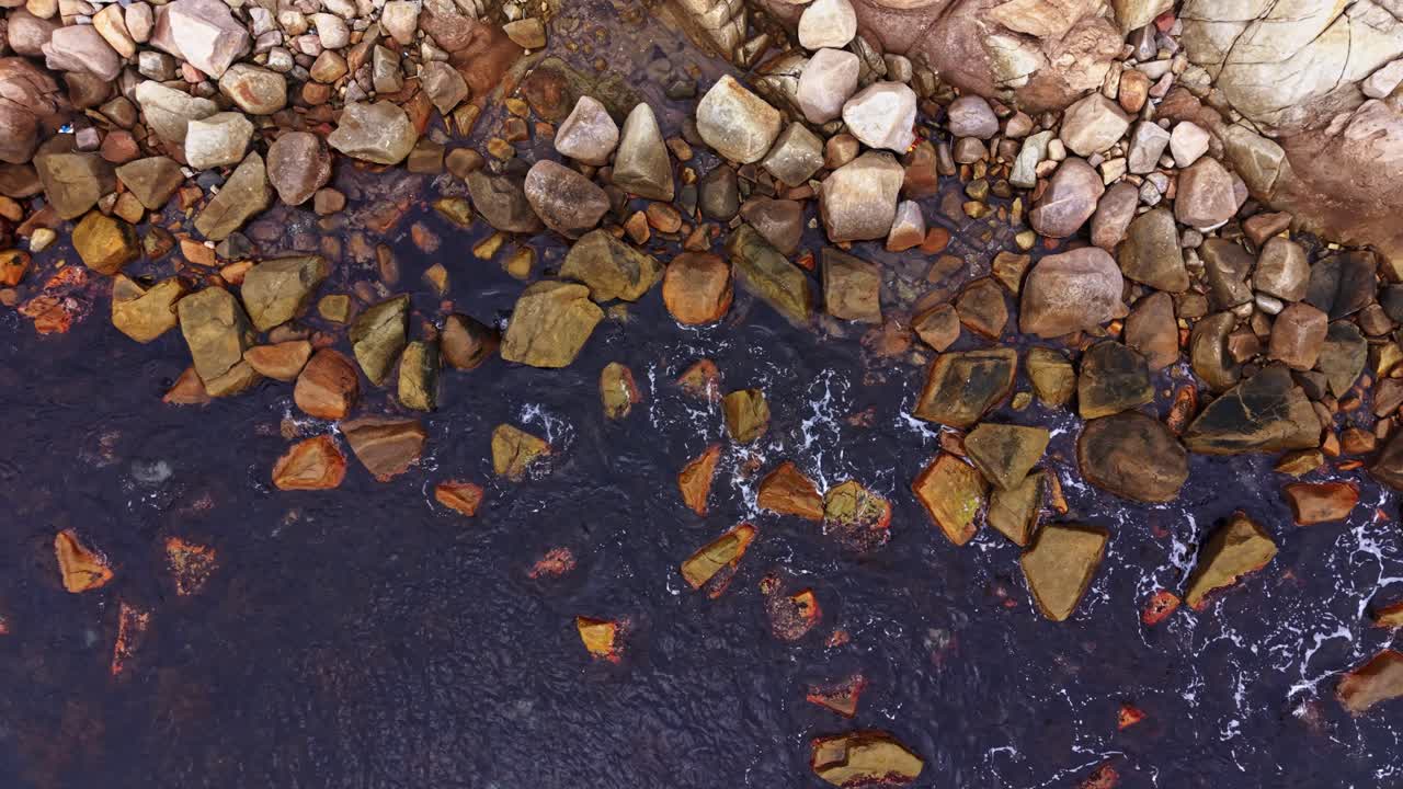 Colorful rocks along the shore captured from above during daytime