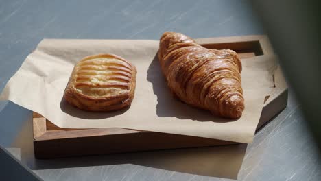 Freshly baked croissant and pastry on a wooden tray