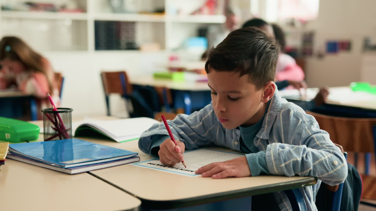A young boy in a classroom working on a math assignment