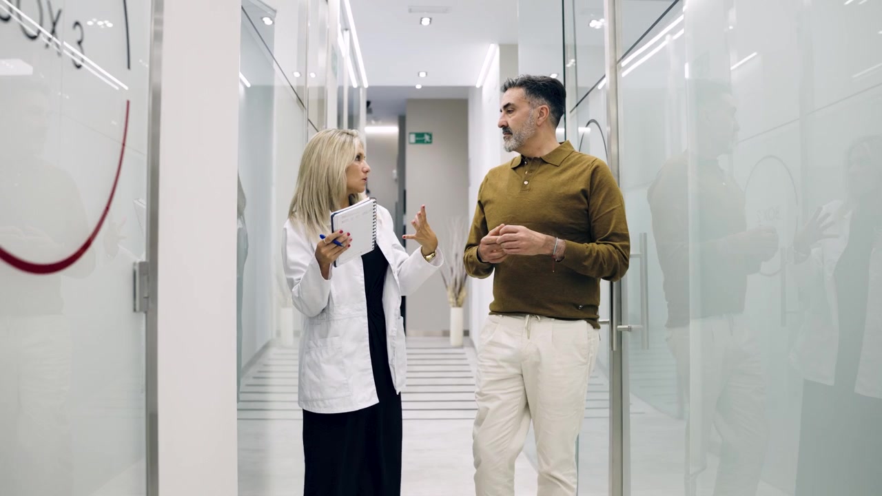 Médico e paciente discutindo tratamento no corredor de uma clínica moderna