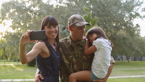 happy military couple of parents and daughter taking selfie