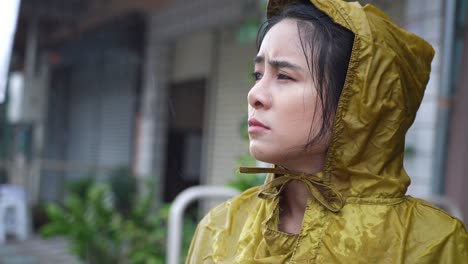 young beautiful asian female wear yellow hoody raincoat feeling sad and disappoint in the pouring rain day, rainy season weather climate, feeling blue and lonely, bad stormy sorrow unhappy vibe