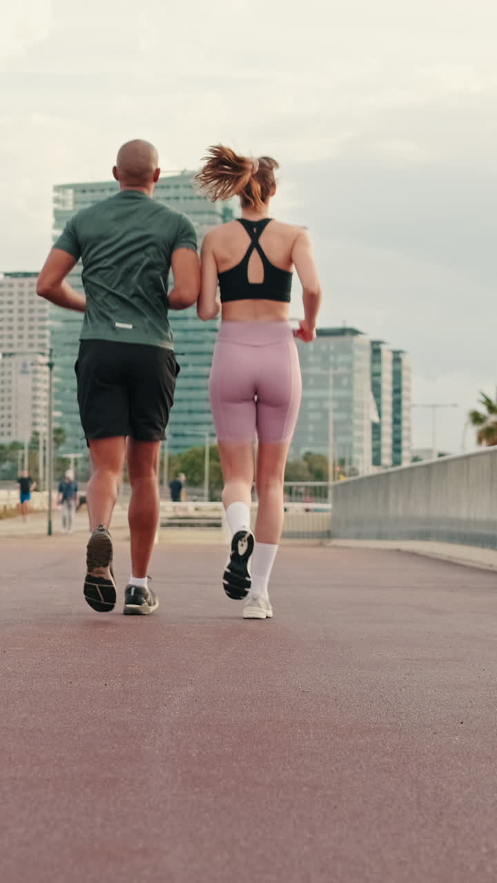 Coppia che corre su passeggiata urbana con edifici cittadini