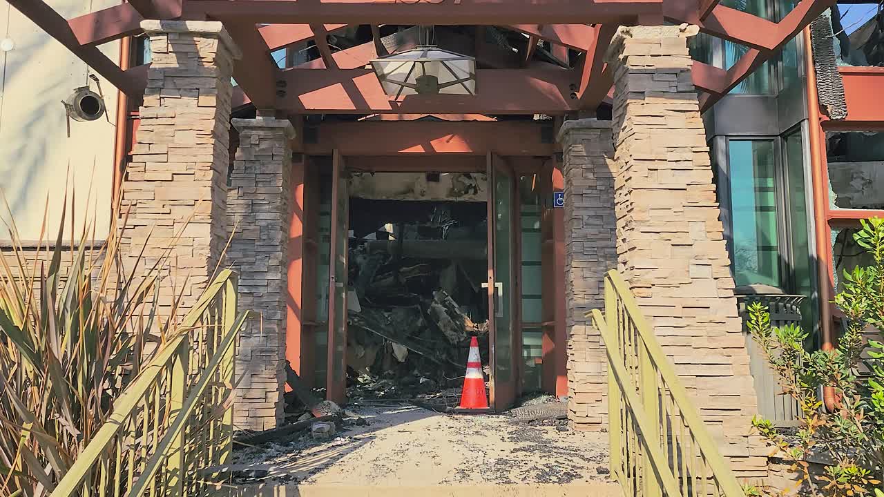 Smooth dolly into remains of care home with handicap sign after fire damage in LA fires, charred walls and debris