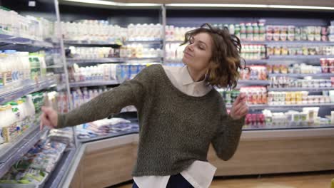 young woman dancing through grocery store aisles. excited woman having fun, dancing supermarket. slow motion