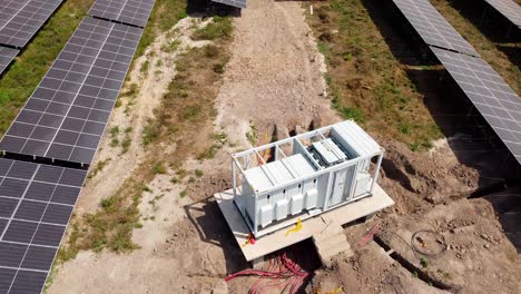 solar photovoltaic field industrial containerized inverter module with visible dc combiner box cables during installation -aerial low close-up view