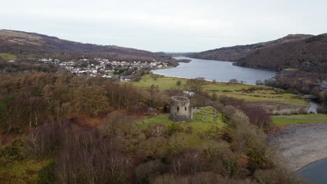 una vista aérea del castillo de dolbadarn en un día nublado, volando de izquierda a derecha alrededor del castillo con la ciudad de llanberis al fondo, gwynedd, gales, reino unido