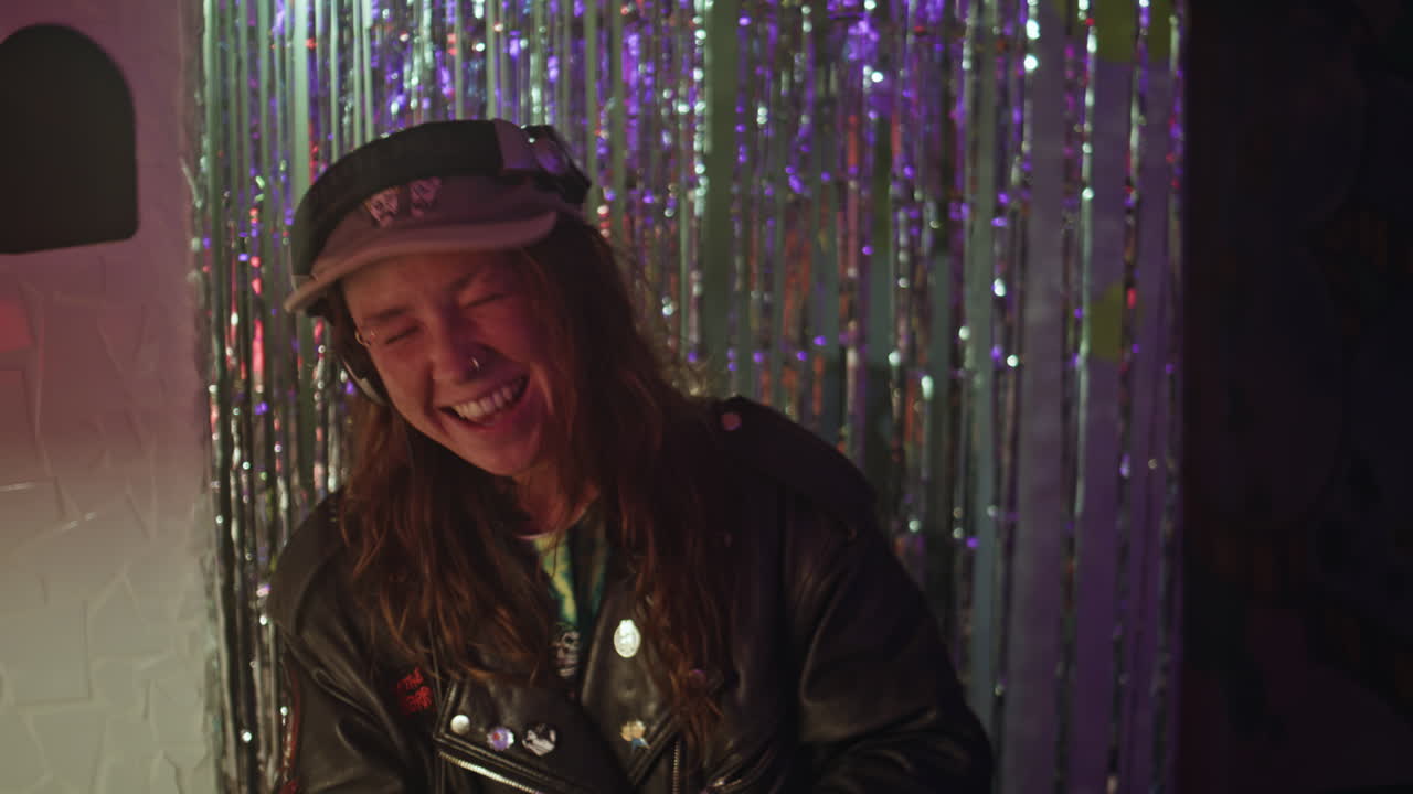 Smiling disc jockey playing music performance at club in headphones closeup