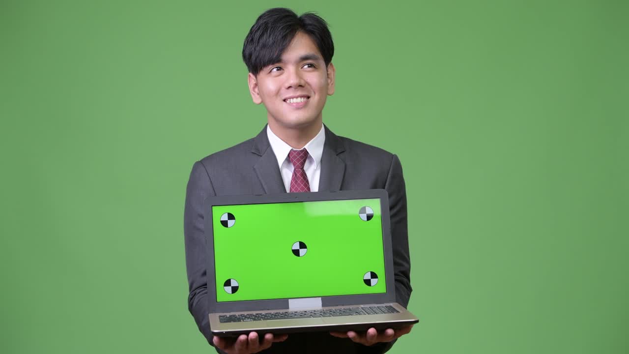 젊은 잘생긴 아시아 사업가 노트북을 보여줍니다.