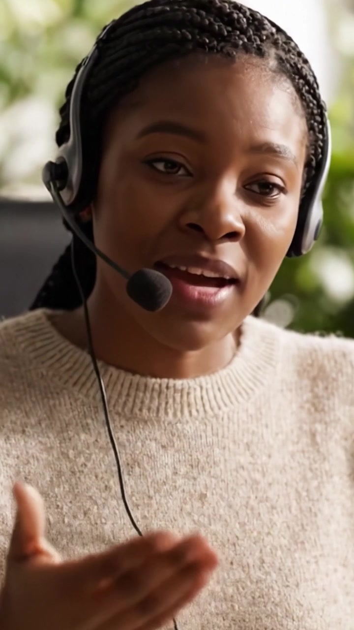 Un professionista concentrato impegnato in una conversazione, che mostra competenze di assistenza clienti ed empatia con un sorriso caloroso in un ambiente luminoso.