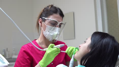 mujer en el higienista dental recibiendo blanqueamiento dental profesional y limpieza por ultrasonido. dentista usando eyector de saliva o bomba dental para evacuar saliva. filmado en 4k