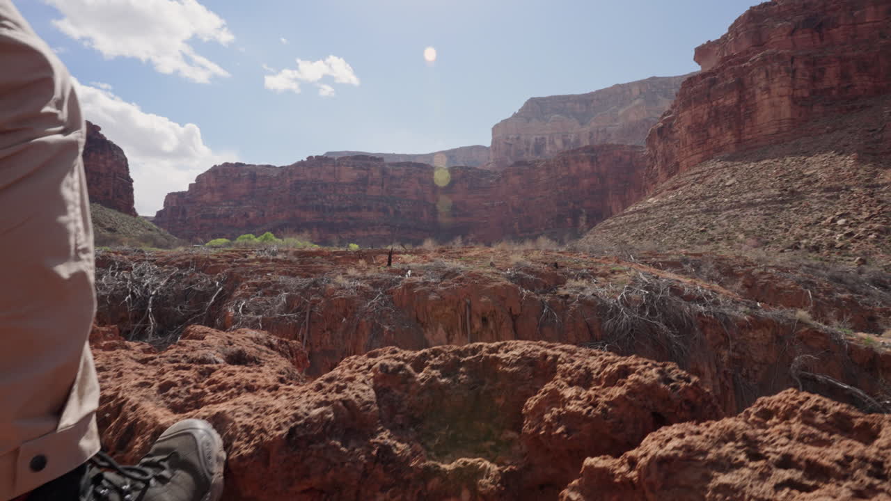 hombre con botas de senderismo da un paso adelante durante una caminata en el desierto, con vistas al vasto paisaje del valle y las formaciones rocosas por delante - concepto: viaje, adelante, logro, lo hizo, éxito