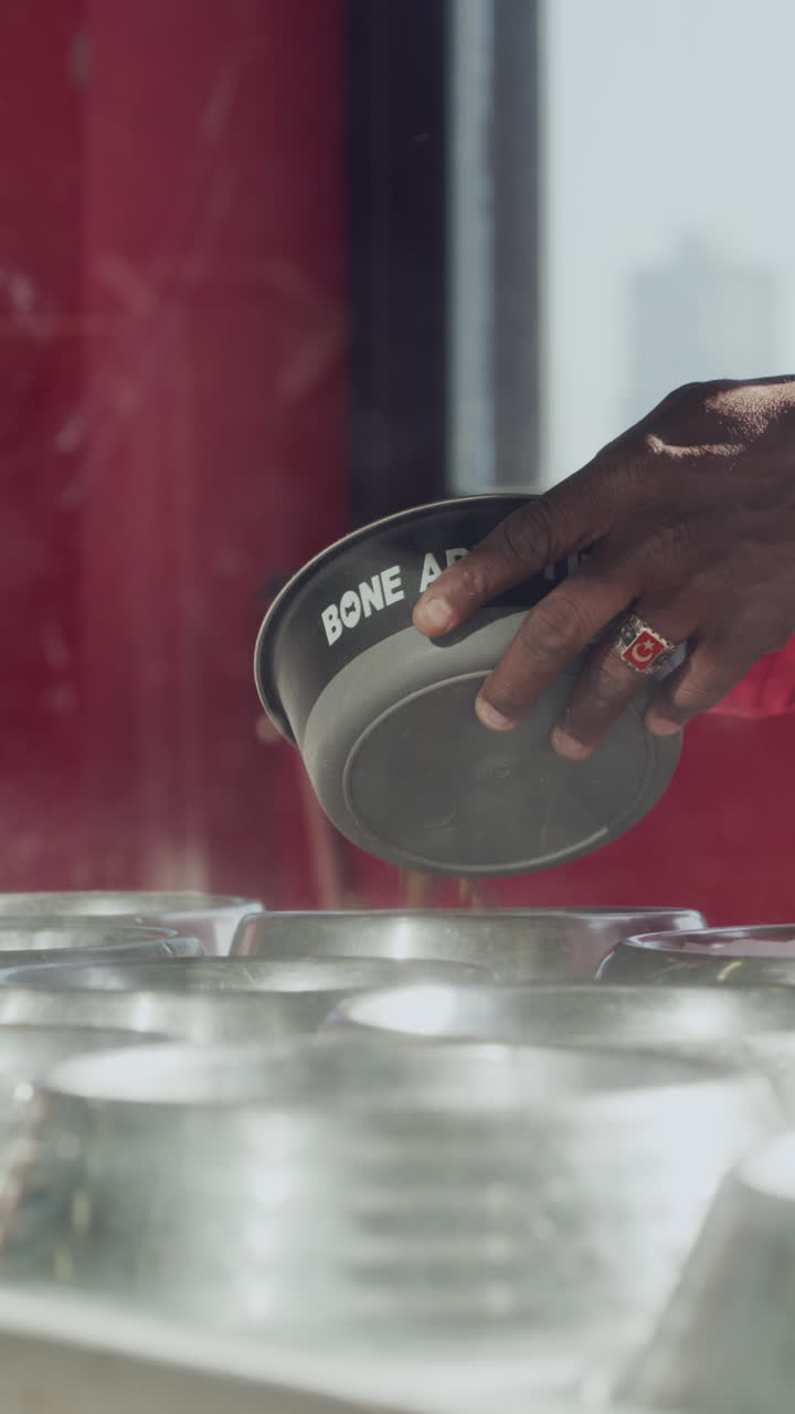 Worker's Hands Placing a Steaming Bowl in a Kitchen