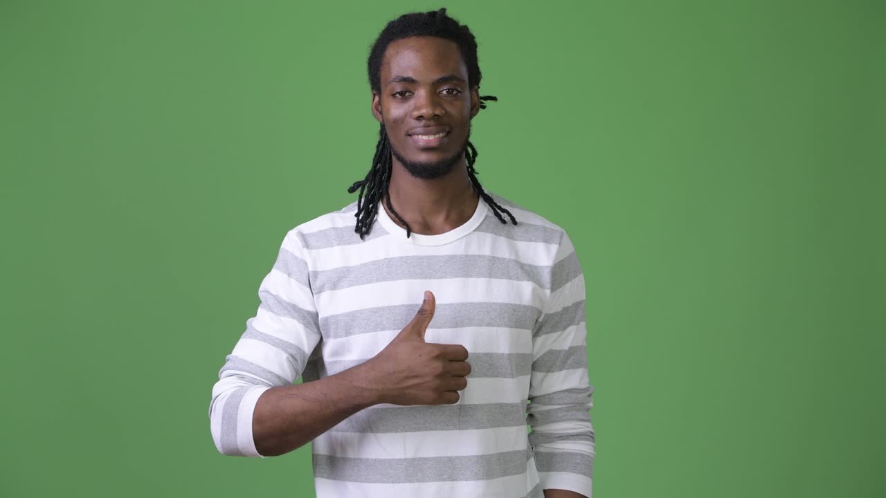 joven hombre africano guapo con dreadlocks contra un fondo verde