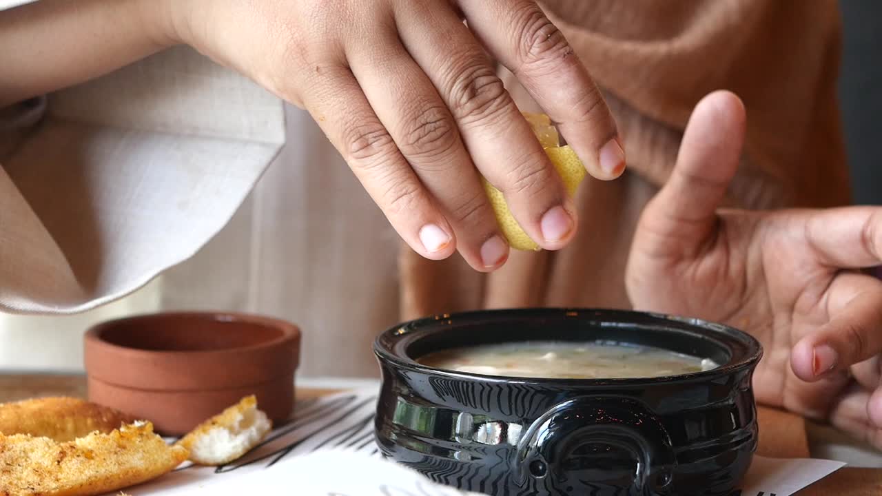 una mujer exprimiendo limón sobre la sopa.