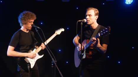 banda de rock de concierto actuando en el escenario con dos guitarras eléctricas cantantes. video musical punk, heavy metal o grupo de rock. banda de instrumentos de cámara lenta de dos hombres