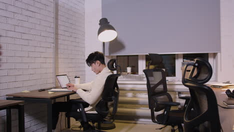 mujer joven con café para llevar entrando a la oficina, sentada en el escritorio y comenzando su trabajo diario mientras su colega masculino escribe algo en el cuaderno